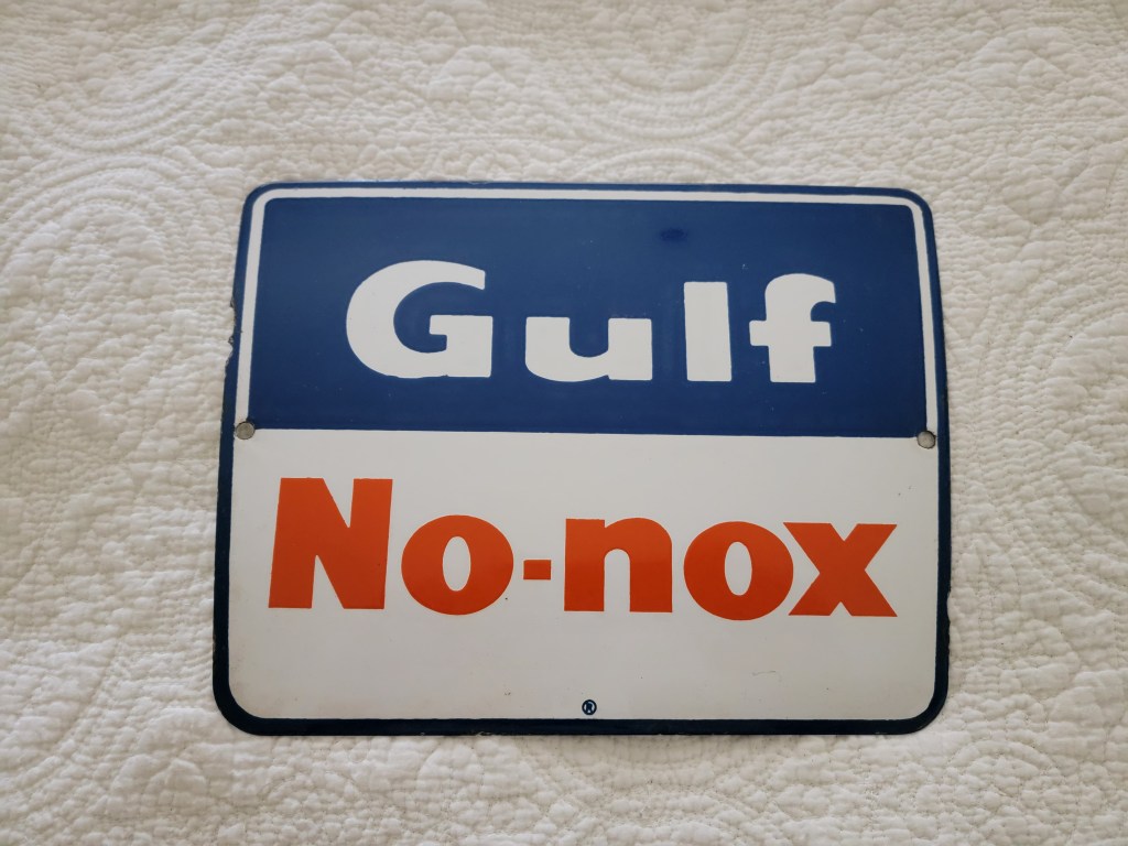 A vintage Gulf Oil sign featuring the words 'Gulf' in white and 'No-nox' in orange, set against a blue background.