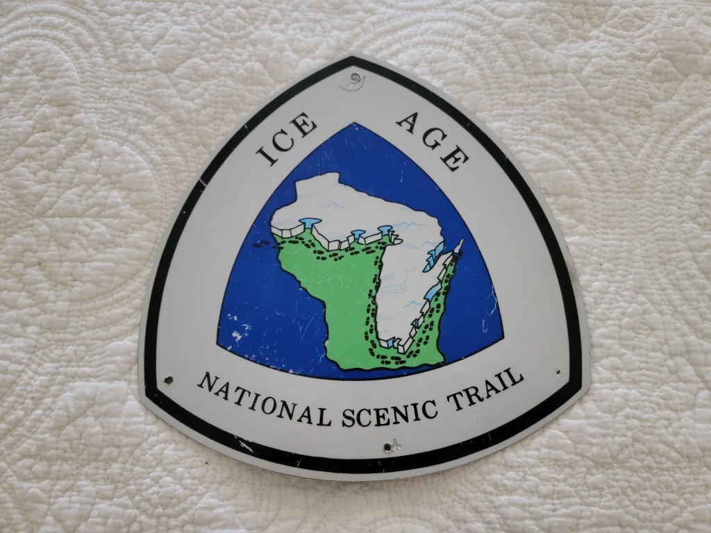Sign for the Ice Age National Scenic Trail featuring a stylized map of Wisconsin.