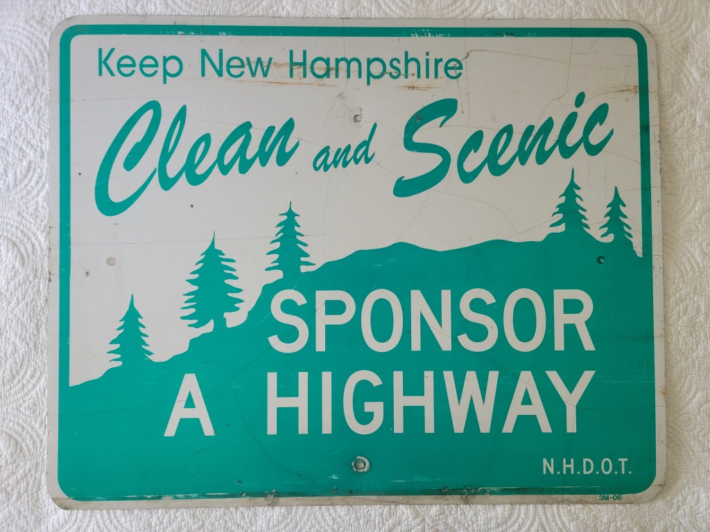 A weathered sign that says 'Keep New Hampshire Clean and Scenic' with the phrase 'Sponsor a Highway' and includes trees in the design.
N.H.D.O.T. street sign