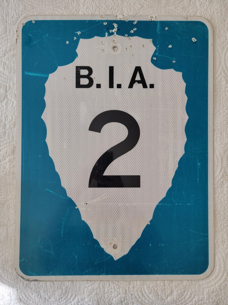 A weathered blue and white road sign displaying 'B.I.A. 2'.
Bureau of Indian Affairs Arrowhead street route sign 2