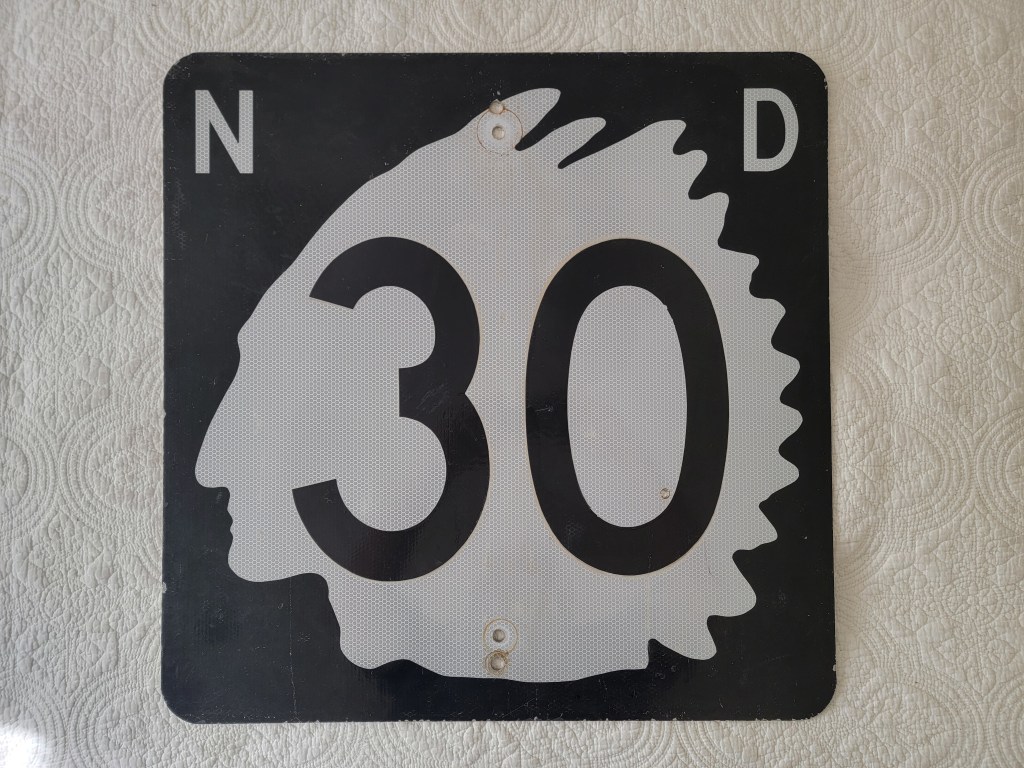 Black and white traffic sign displaying the number 30, with a profile silhouette integrated into the design.
North Dakota Indian chief street sign route 30