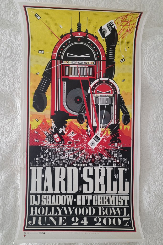 A colorful concert poster for the 'Hard Sell' event featuring DJ Shadow and Cut Chemist at the Hollywood Bowl on June 24, 2007. The design includes two robotic figures and various music-related graphics.

DJ Shadow Hard Sell Cut Chemist Hollywood Bowl June 24 2007
signed poster dj shadow